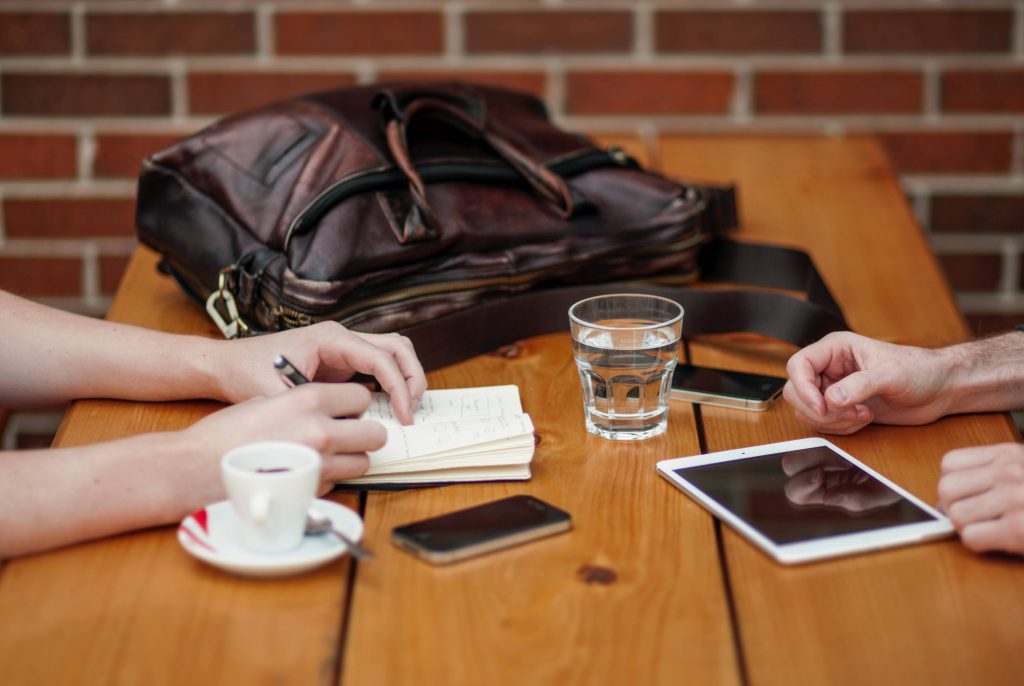 Two mobile devices on a wooden table, with someone using a tablet