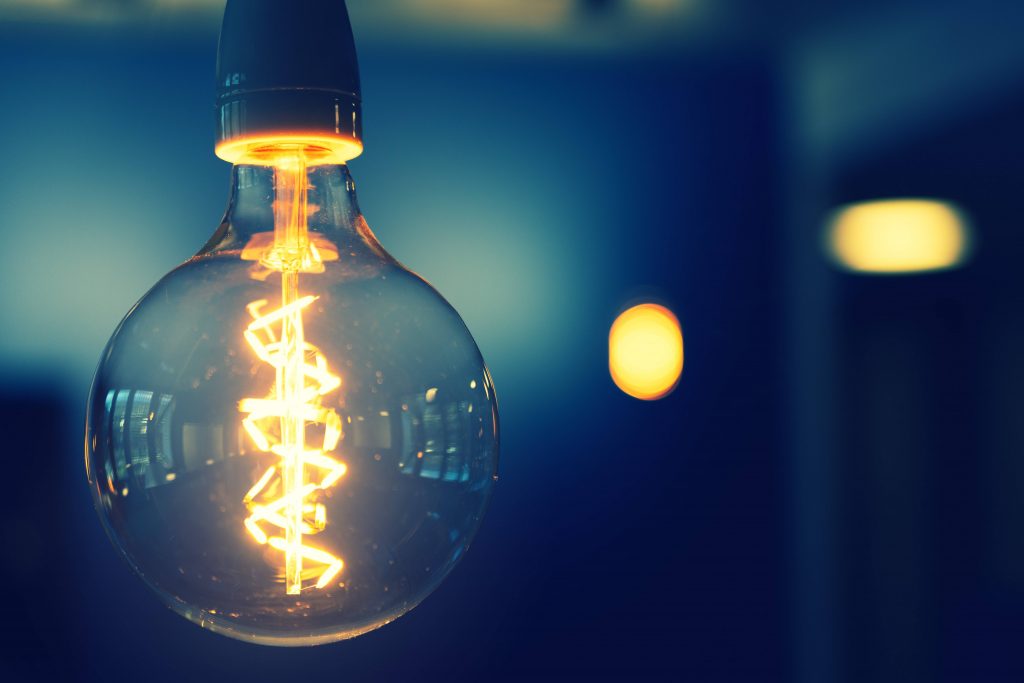 A close-up of a lightbulb, with two blurred lightbulbs in the background