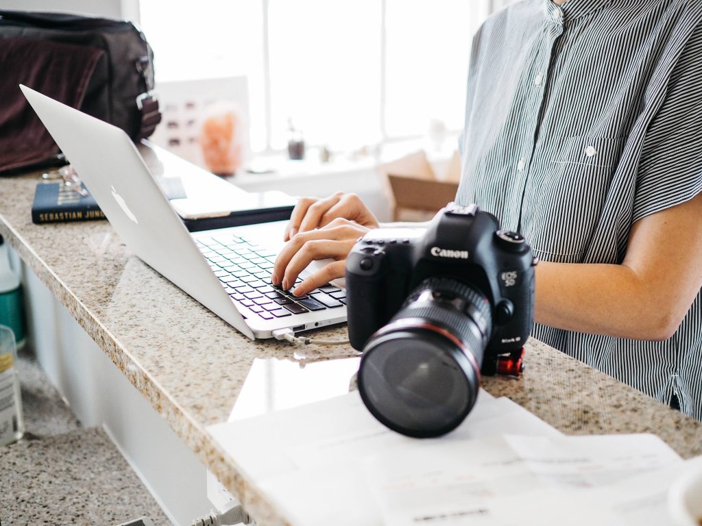 Camera next to a man typing on a MacBook Pro